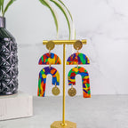 Colorful U-shaped pride earrings on a gold stand with a white background