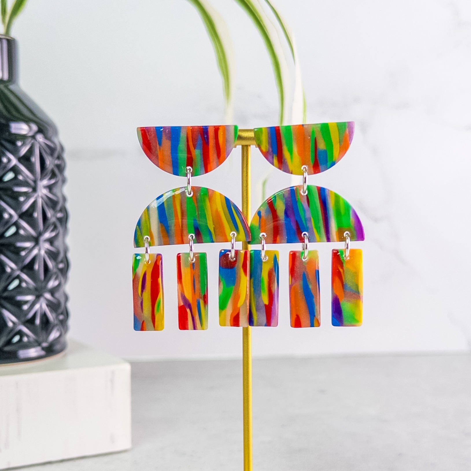 Colorful pride earrings on a stand with a white background