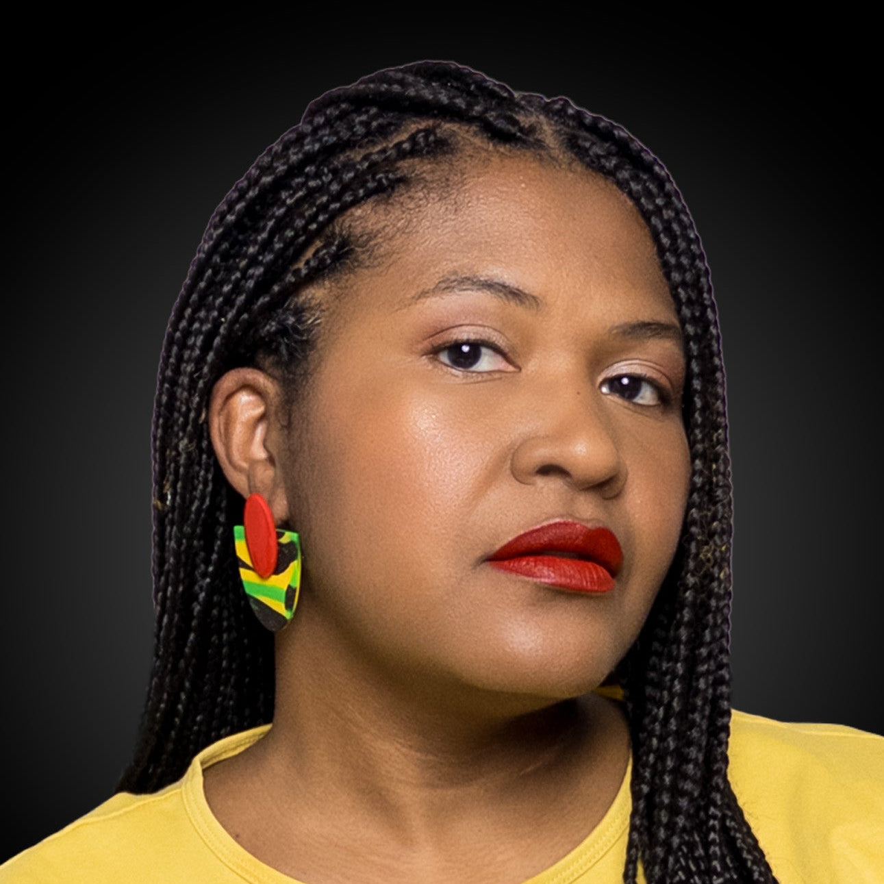 Woman with braided hair wearing black history month juneteenth black red green yellow abstract large statement dangle lightweight multicolored festive stud earrings