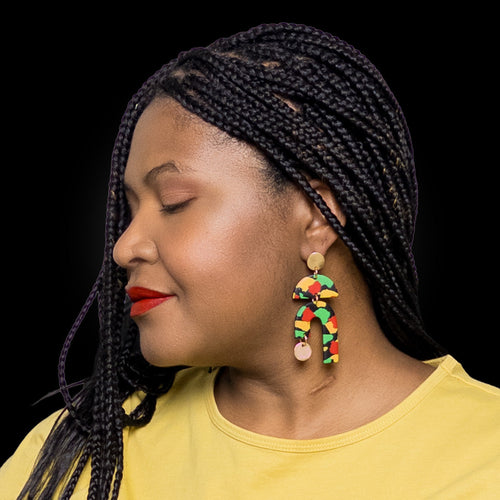 Woman with braided hair wearingblack history month juneteenth black red green yellow abstract large statement dangle lightweight multicolored festive earrings