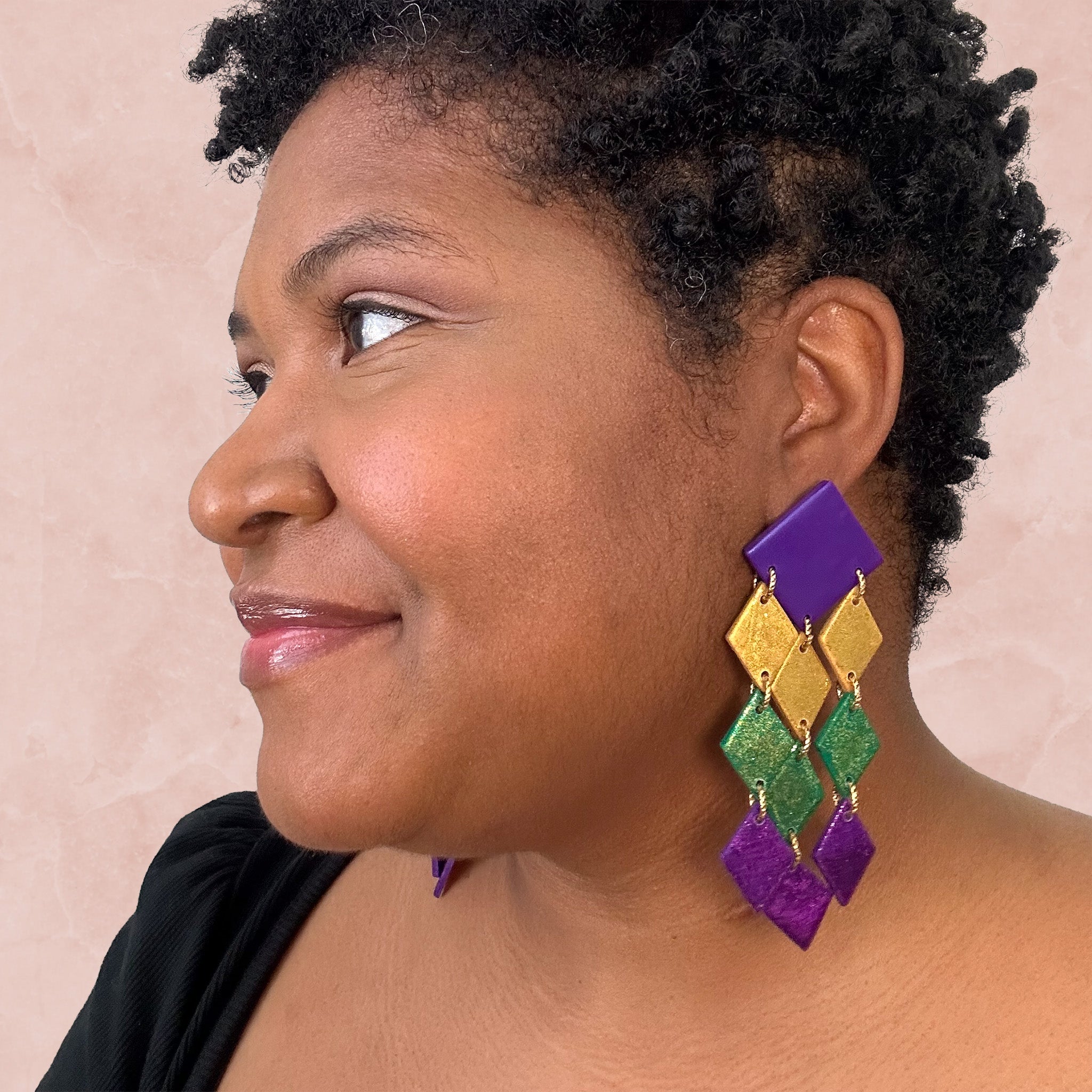 stunning statements clay mardi gras dangle lightweight large big statement glitter shiny purple green gold earrings on a model