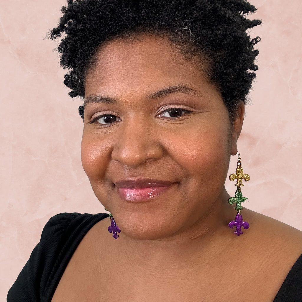 stunning statements clay mardi gras dangle lightweight large big statement glitter shiny purple green gold fleur de lis earrings on a model