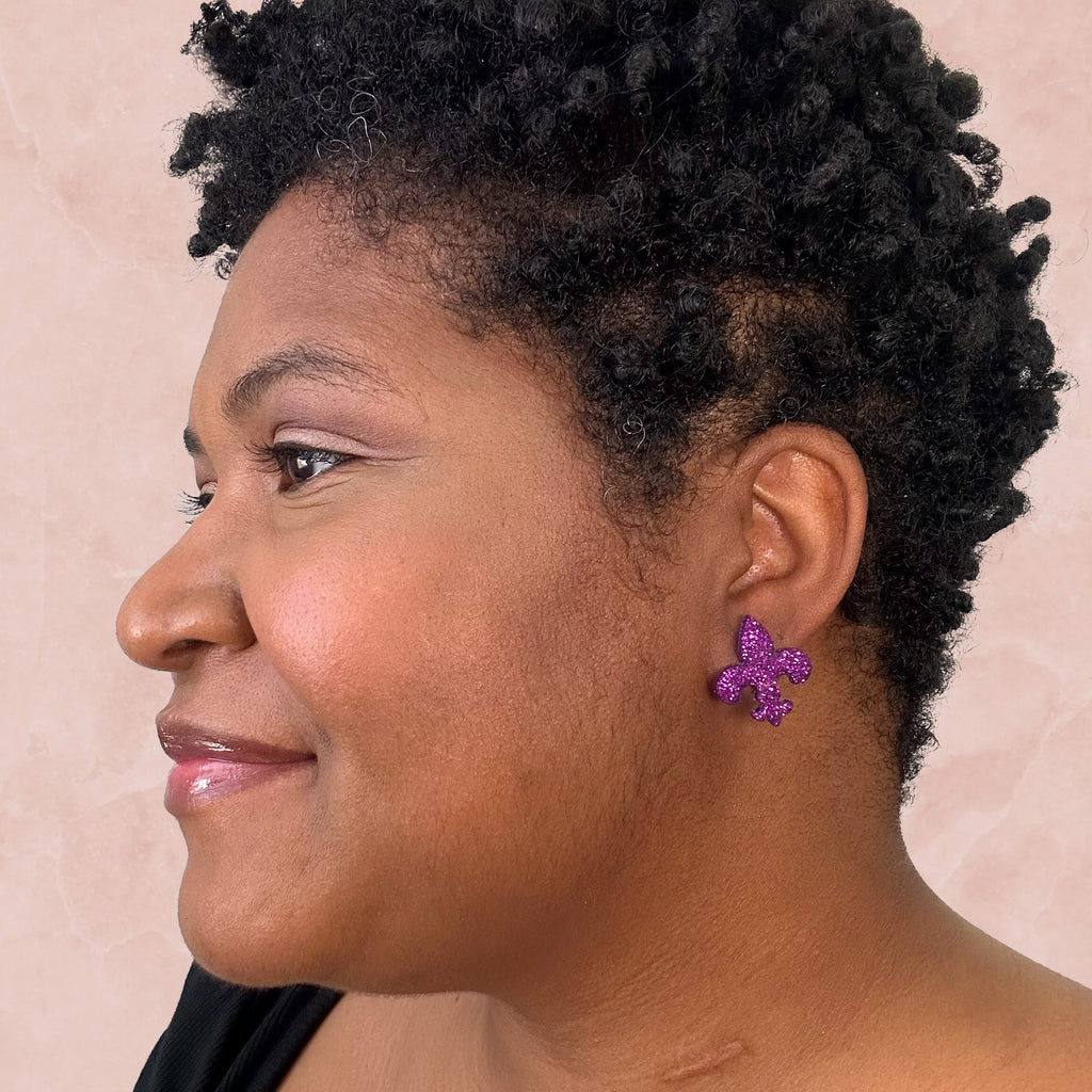 stunning statements clay mardi gras lightweight large big statement glitter shiny purple green gold fleur de lis stud earrings on a model
