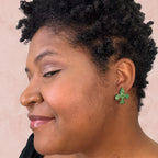 stunning statements clay mardi gras lightweight large big statement glitter shiny purple green gold fleur de lis stud earrings on a model